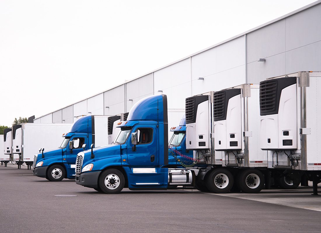 Insurance by Industry - Row of Blue Trucks With White Trailers Parked at a Loading Station at a Warehouse
